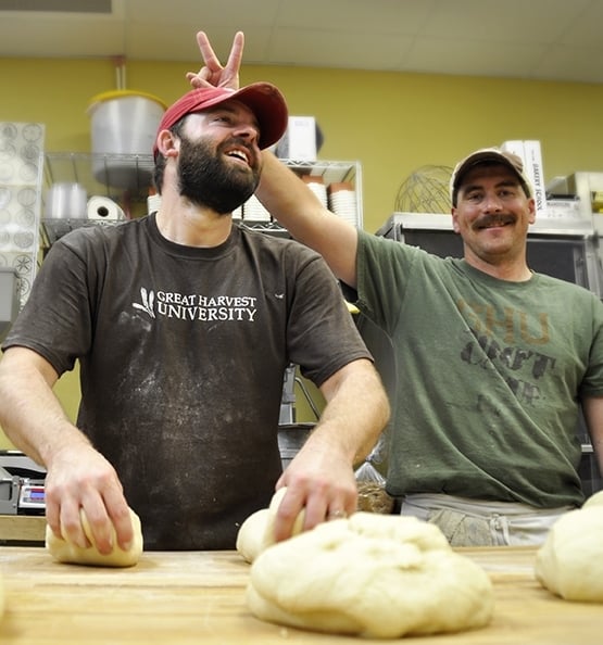 This is a photo of two bakers smiling and kneading bread