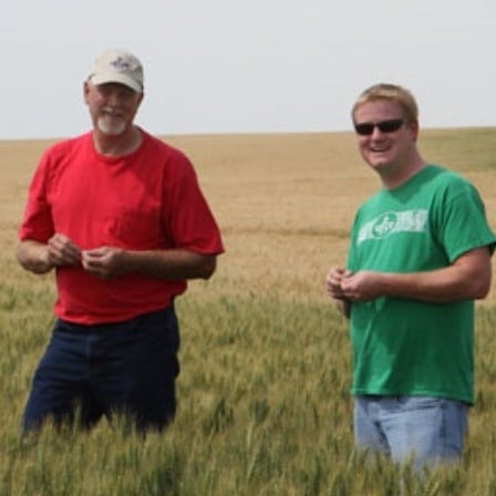 This is a photo of a wheat farmer and a Great Harvest wheat manager in a wheat field.