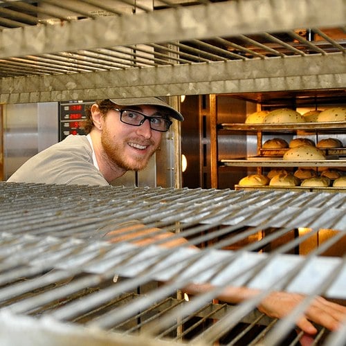 great harvest team member grabbing bread out of an oven