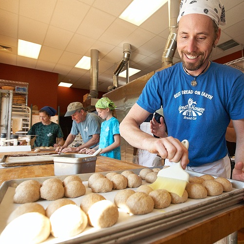 Great harvest employee brushing dough with egg wash